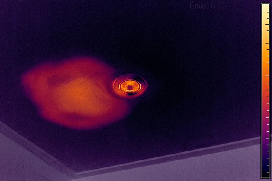 Warmtebeeld van een plafond, waarop zich naast een inbouwspot een afwijkende zone aftekent